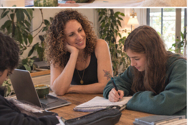 Nicole listening attentively while a student writes during an English lesson